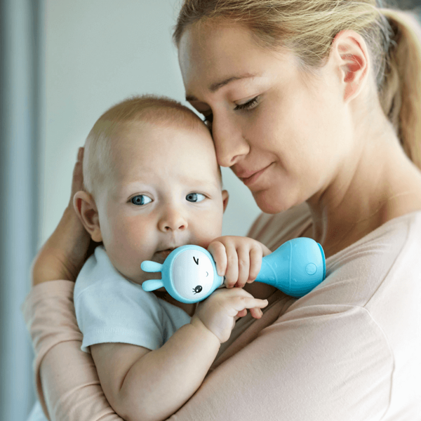 Mama trzyma w objęciach dziecko, które przy twarzy ma niebieskiego królika