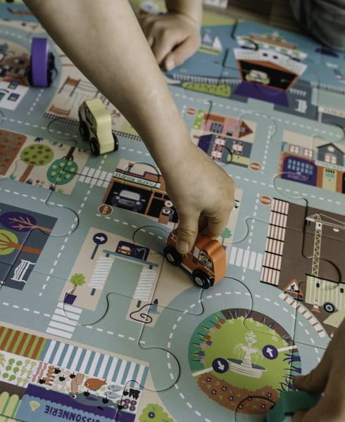 Puzzle z motywem miasta i drewniane samochodziki jeżdżące po nich