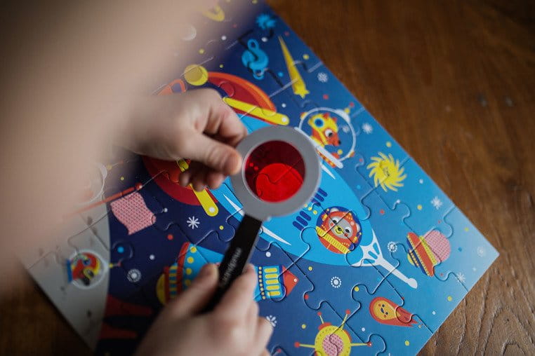 Puzzle z elementami z kosmosu i ze szkłem przez które widać ukryte elementy